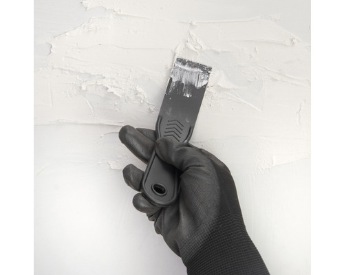Hand mit Handschuh und Spachtel beim Verputzen einer Wand
