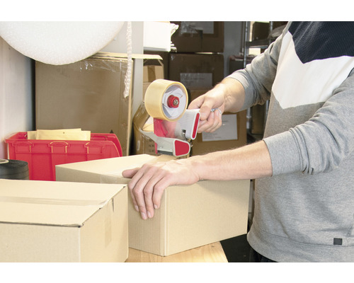 Eine Person verschließt einen Karton mit einem Klebebandabroller.