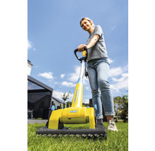 Frau benutzt eine Gloria Multibürste auf Rasen für die Gartenpflege.