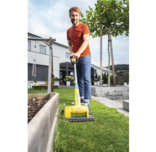 Mann benutzt einen gelben Vertikutierer im Garten.