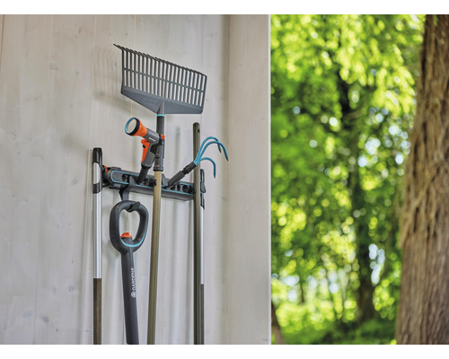 Gartengeräte wie Rechen, Spaten und Gartenschlauch hängen an einer Wandhalterung.