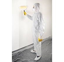 Person mit Schutzanzug streicht Wand mit Farbroller