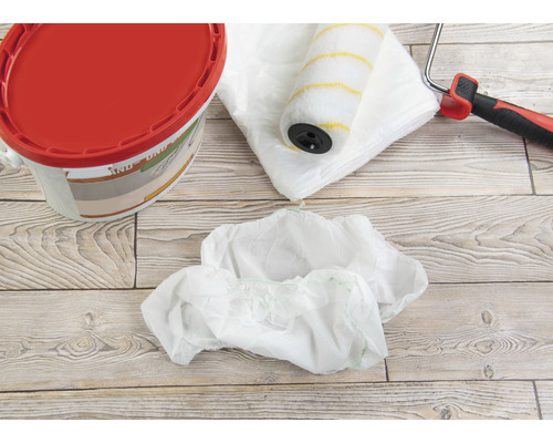 Farbeimer, Farbroller, Abdeckfolie und Schuhüberzieher für Malerarbeiten.