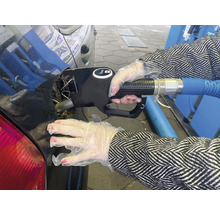 Eine Person in Handschuhen tankt Dieselkraftstoff in ein Auto.