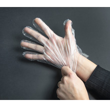 Eine Hand, die einen transparenten Einmalhandschuh anzieht