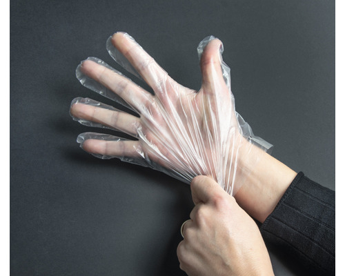 Eine Hand, die einen transparenten Einmalhandschuh anzieht