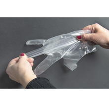Frau zieht einen transparenten Einmalhandschuh an