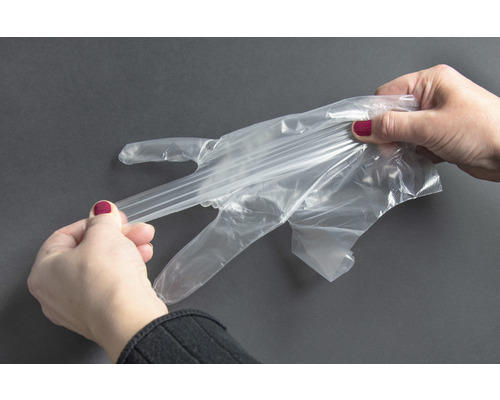 Frau zieht einen transparenten Einmalhandschuh an