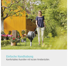 Frau benutzt eine Gartenschlauchbox im Garten.