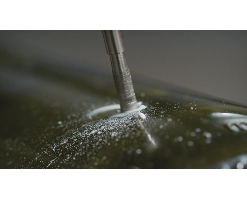 Metallbohrer bohrt Loch in Glasflasche