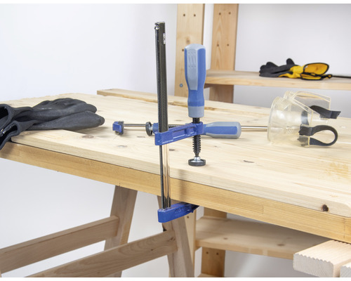 Werkbank mit Schraubzwinge, Arbeitshandschuhen und Schutzbrille
