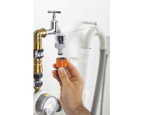 Hand befestigt Gardena-Adapter an Wasserhahn für Gartenbewässerung