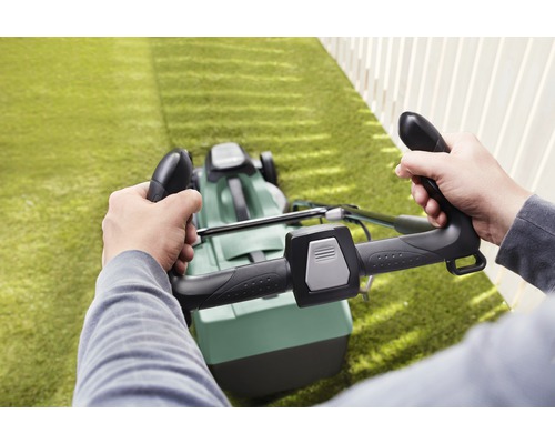 Person bedient einen Rasenmäher auf einer Rasenfläche