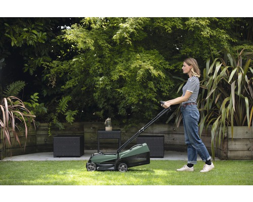 Eine Frau benutzt einen Rasenlüfter im Garten.