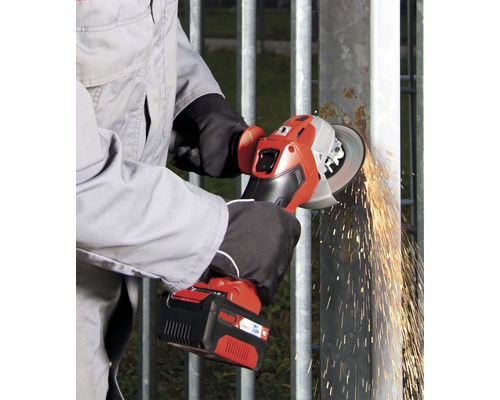 Akkubetriebener Winkelschleifer im Einsatz an einem Metallzaun, Funken fliegen
