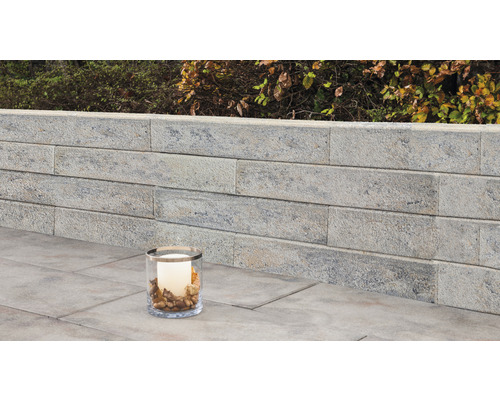 Gartenmauer aus Stein mit dekorativer Kerze im Glas
