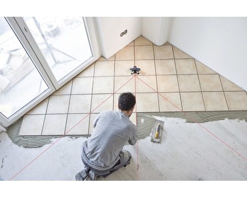 Fliesenleger verlegt Fliesen mit Hilfe eines Laser-Nivelliergeräts