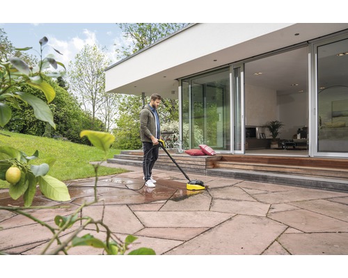 Mann reinigt Terrasse mit einem Terrassenreiniger
