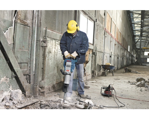 Bauarbeiter mit Presslufthammer bei Abbrucharbeiten in einem Gebäude.