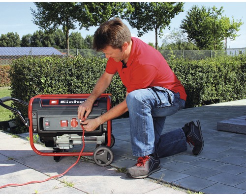 Mann schließt ein Kabel an einen Einhell Stromerzeuger im Freien an.