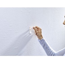 Frau befestigt einen Klebehaken an einer Wand