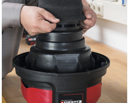 Ein Mann setzt einen Filterschaumstoff auf einen Einhell Staubsauger.