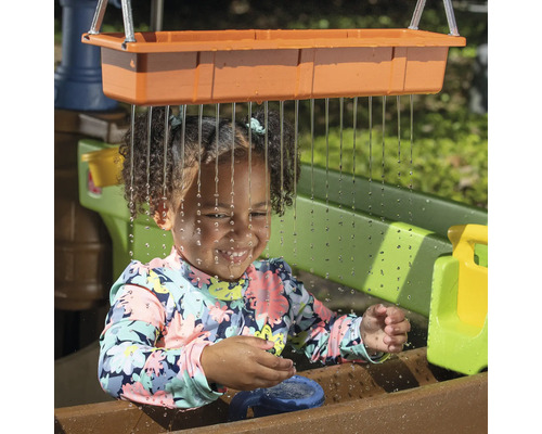 Mädchen spielt mit Wasserspieltisch im Garten