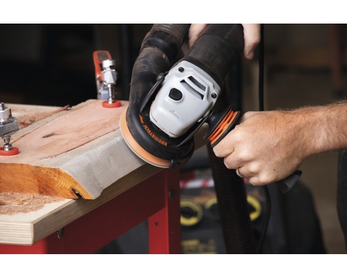 Eine Person schleift ein Holzbrett mit einem Winkelschleifer.