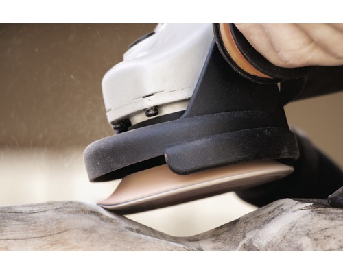 Nahaufnahme eines Winkelschleifers beim Bearbeiten eines Holzstücks