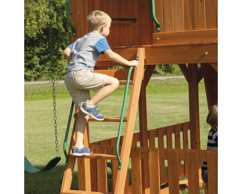 Kind klettert auf einem Holzspielplatz mit Leiter.
