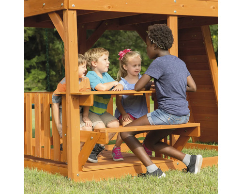 Kinder spielen auf einem Holzspielplatz mit Picknicktisch.