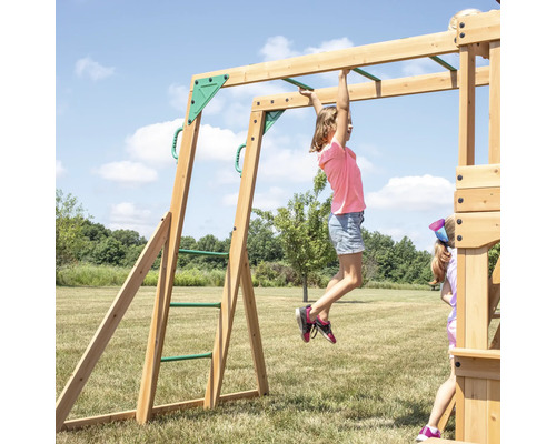 Kind hängt an einer Holzschaukel mit Sprossenleiter im Garten.