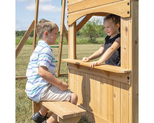 Kinder spielen an einem Spielturm aus Holz mit Fenster und Sitzbank