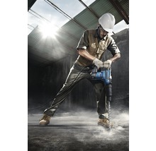 Ein Bauarbeiter mit Schutzhelm bohrt mit einem Bohrhammer in den Boden.