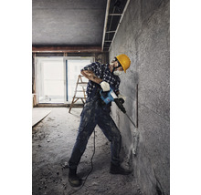 Handwerker mit Abbruchhammer bei Renovierungsarbeiten in einem Raum.