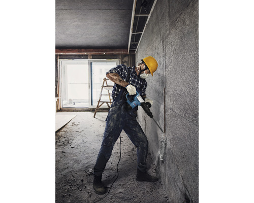Handwerker mit Abbruchhammer bei Renovierungsarbeiten in einem Raum.