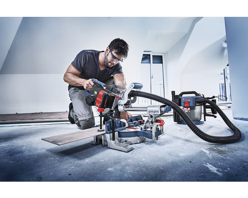 Handwerker bei der Arbeit mit einer Kapp- und Gehrungssäge in einem Raum.