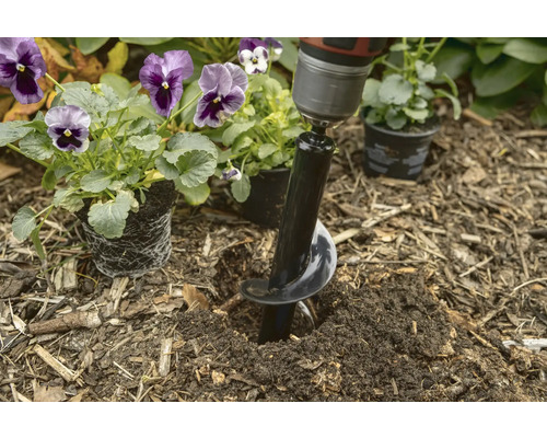 Bohrer mit Erdlochbohrer im Einsatz zum Pflanzen von Blumen im Garten