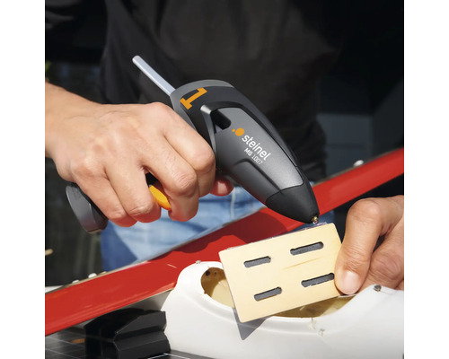 Eine Person verwendet eine Steinel MG 1007 Klebepistole, um ein Holzstück zu befestigen.