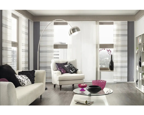 Helles Wohnzimmer mit Schiebevorhängen, Sofa, Sessel und Stehlampe.