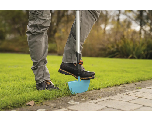Person verwendet einen Rasenkantenstecher im Garten.