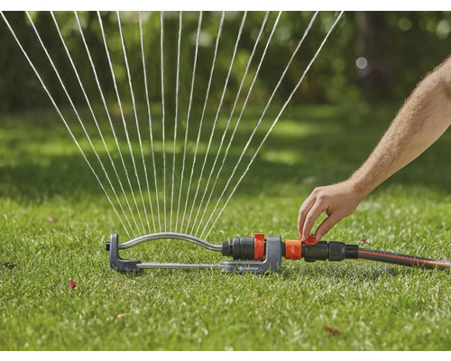 Rasensprenger bewässert Rasenfläche mit Wasserstrahlen