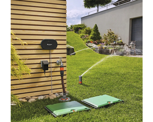 Szene mit Bewässerungssystem im Garten mit Steuergerät, Wasserhahnanschluss und versenkbarem Viereckregner