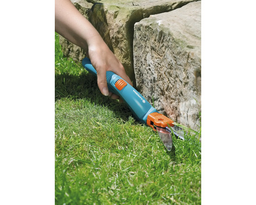 Gartenschere im Einsatz zum Rasenkantenschneiden an einem Stein