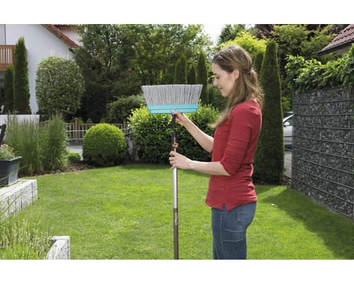 Frau bedient einen Straßenbesen im Garten.