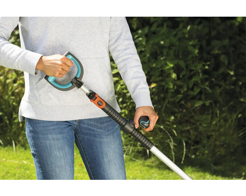 Person benutzt einen Unkrautstecher im Garten.