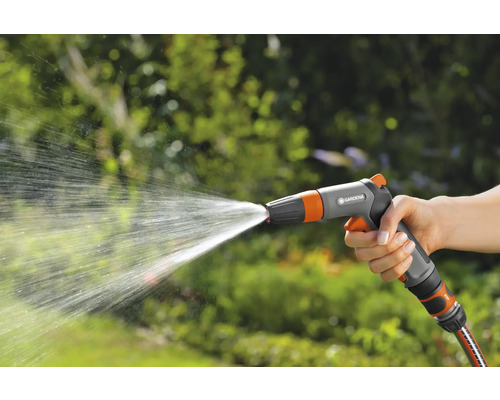 Eine Hand hält eine Gartenspritze, aus der Wasser austritt.
