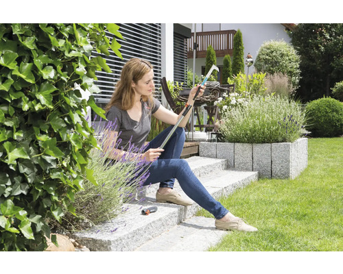 Frau sitzt im Garten und inspiziert einen Obstpflücker