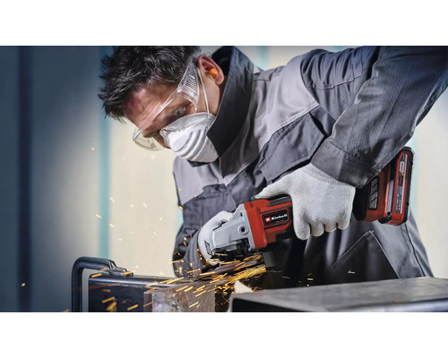 Ein Mann schleift Metall mit einem Einhell Akku-Winkelschleifer und trägt dabei Schutzausrüstung.