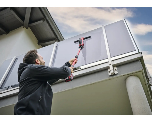 Mann reinigt Glasbrüstung mit einem Akku-Fensterreiniger.